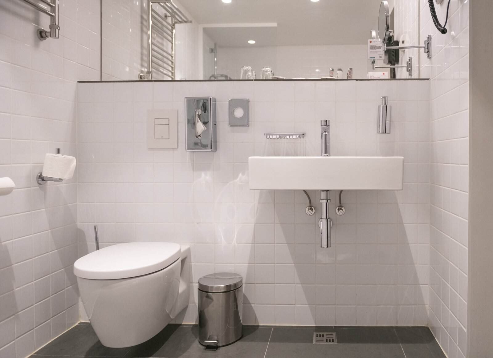 Modern white bathroom with toilet and sink in a clean, minimal design.